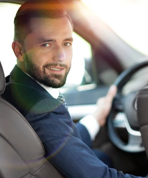 Businessman sitting at the wheel of a car and looking at the camera — Stock Photo, Image