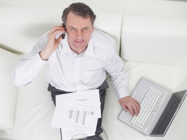 sandalyede oturan ve bir smartphon üzerinde konuşurken işadamı