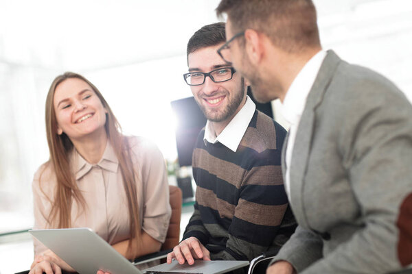 Three happy employees working on line with a tablet
