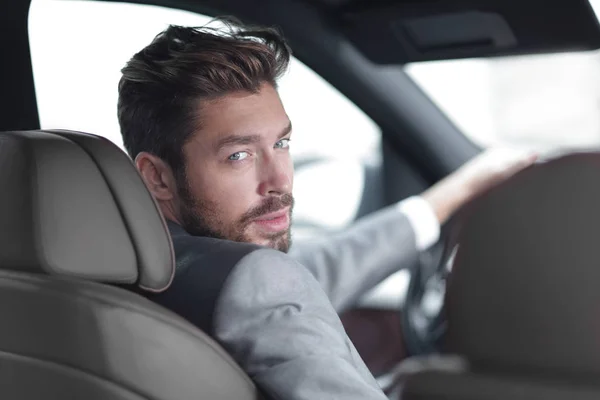 Vista posteriore, giovane che guida la sua auto, guardando la macchina fotografica — Foto Stock