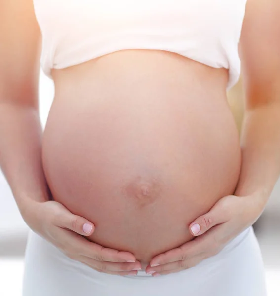 Primer plano de una mujer embarazada poniendo sus manos sobre su barriga . — Foto de Stock
