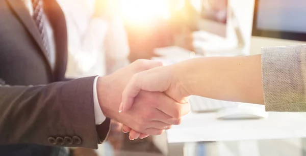 Hombre de negocios estrechando la mano con un socio de negocios sentado cerca de su escritorio — Foto de Stock