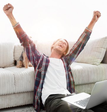 mutlu genç adam köpeğiyle oturma odasında exults