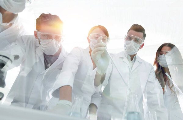 учёные, работающие с пробирками и микроскопом в лаборатории
