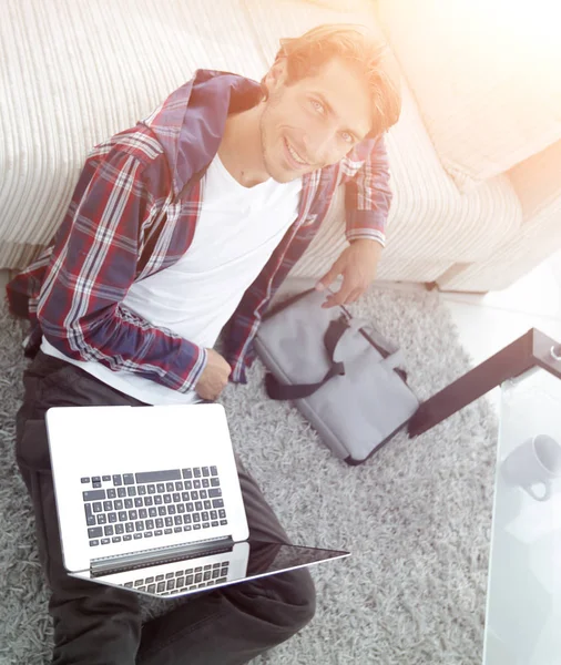 Бізнесмен з ноутбуком сидить на килимі у вітальні . — стокове фото