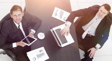 Masada oturan ve kameraya bakarak iki iş arkadaşları.