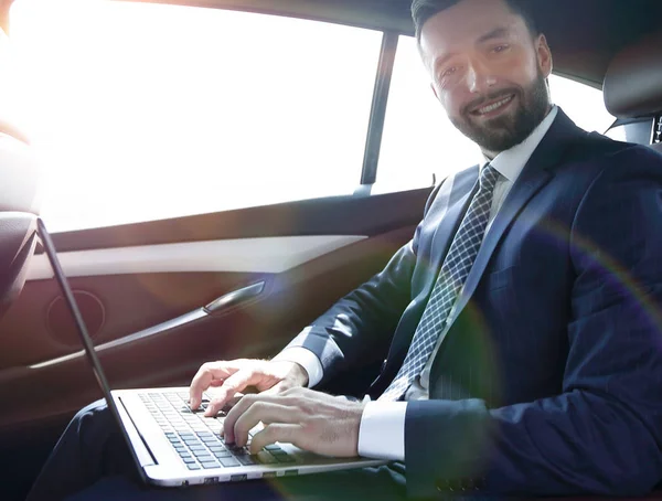 Mladá podnikatelka pracující na svém laptopu, zatímco sedí v c — Stock fotografie