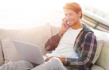 cep telefonu üzerinde konuşurken laptop ile ciddi genç adam