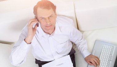 sandalyede oturan ve bir smartphon üzerinde konuşurken işadamı