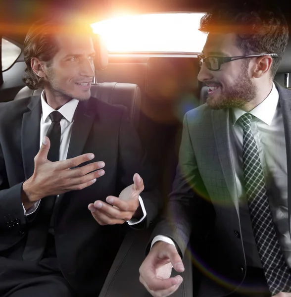 Two businessman talking while sitting in the car — Stock Photo, Image