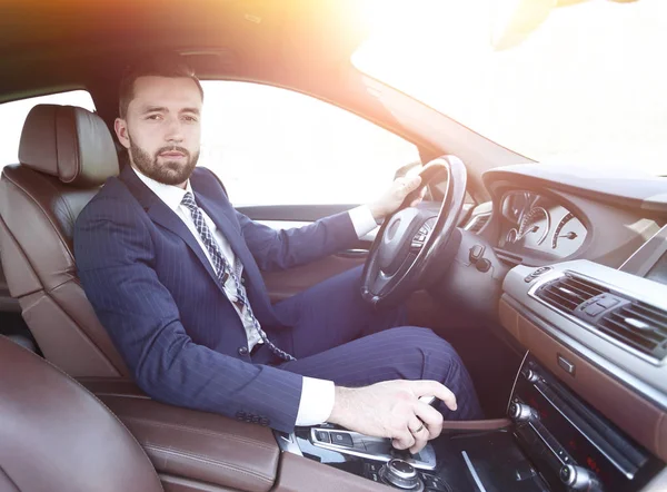 Vista laterale uomo d'affari fiducioso siede al volante di una macchina — Foto Stock