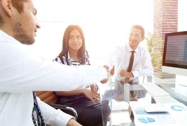 Mannen schudden handen en glimlachen terwijl ze aan het bureau zitten — Stockfoto