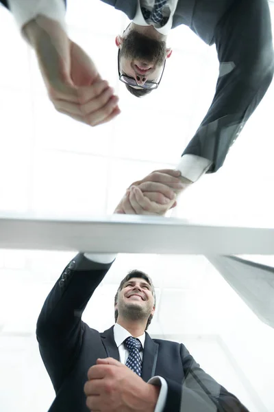 Vista desde abajo. Detrás del cristal. apretón de manos de socios comerciales — Foto de Stock