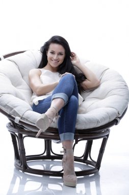 Yuvarlak, yumuşak bir sandalyede dinlenen modern genç kadın.