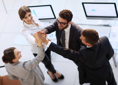 Başarılı bir iş ekibi ofiste birbirlerine beşlik çakıyor.