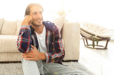 Samimi bir oturma odasındaki halının üzerinde oturan rüya gören bir adamın yakın çekimi.