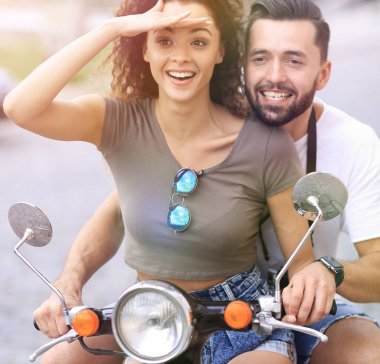 Güzel genç bir çift bir scooter sürme sırasında gülümsüyor