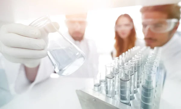 Closeup.a grupo de científicos que estudian el líquido en el vaso t — Foto de Stock