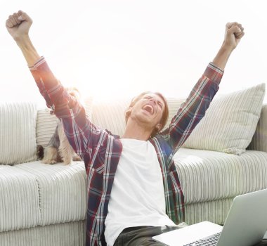 mutlu genç adam köpeğiyle oturma odasında exults