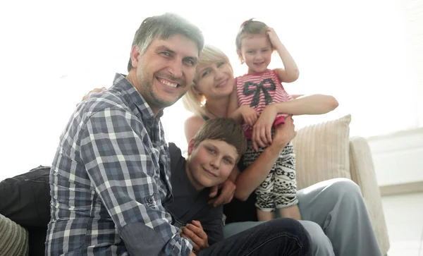 Gezin met twee kinderen elkaar zitten en kijken naar camera — Stockfoto