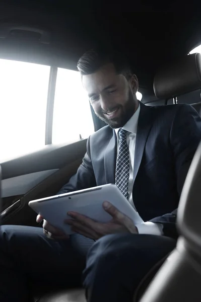 Biznesmen z cyfrowego tabletu, siedzący na tylnym siedzeniu samochodu — Zdjęcie stockowe