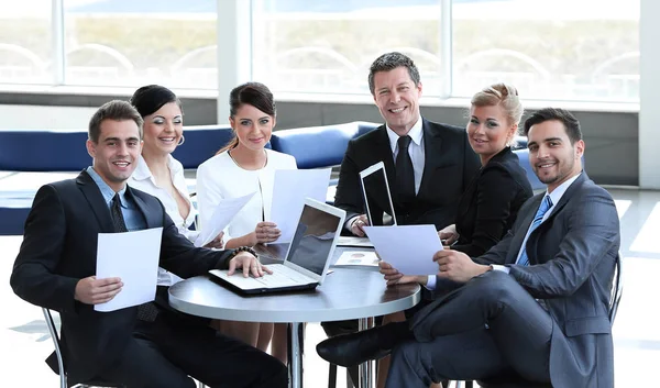 Skupina podnikatelů s dokumenty, které sedí u stolu v hale banky. — Stock fotografie