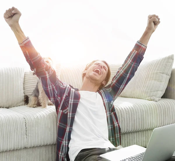 mutlu genç adam köpeğiyle oturma odasında exults