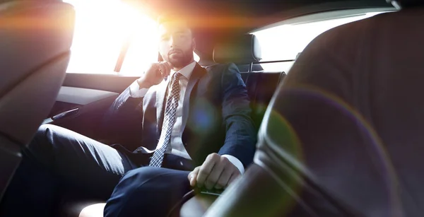 Uomo d'affari che parla al telefono seduto sul sedile posteriore — Foto Stock