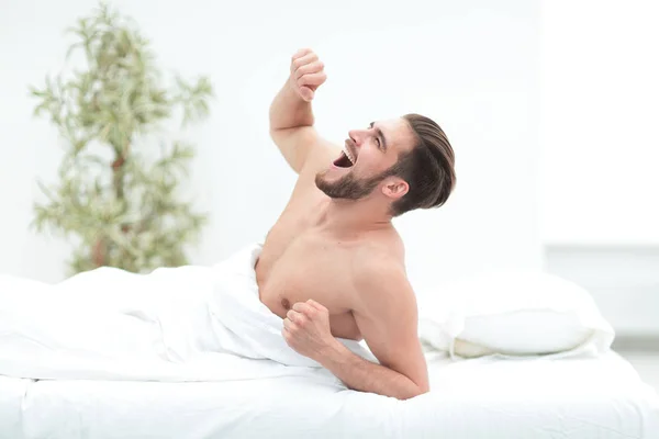 Homem de sucesso boceja, deitado no quarto — Fotografia de Stock