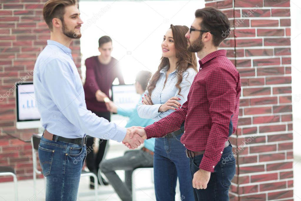 Smiling businessman shaking hands with colleague in office.