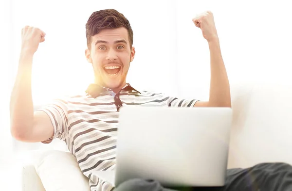 Hombre feliz con el ordenador portátil sentado en el sofá — Foto de Stock