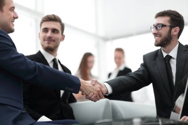 Ortaklar, takım üyelerinin huzurunda anlaşma yapıp el sıkışıyorlar.