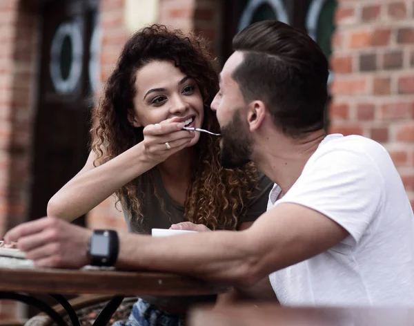 Молода пара насолоджується кавою у вуличному кафе та сміється — стокове фото