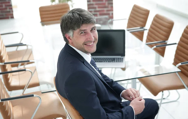 Gerente sonriente sentado en el escritorio en la sala de reuniones . —  Fotos de Stock