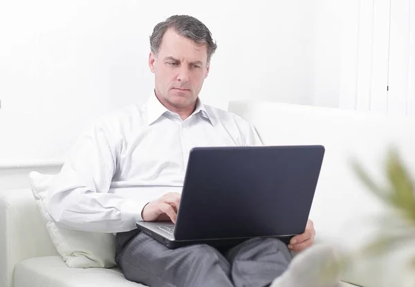Bir otel odasında otururken dizüstü bilgisayarda çalışan iş adamı — Stok fotoğraf