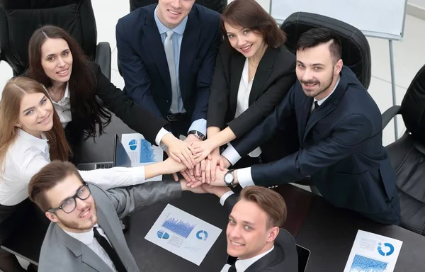 Equipo de negocios con las manos juntas en el escritorio — Foto de Stock