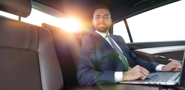 Başarılı adam arabanın içinde otururken dizüstü bilgisayar ile çalışma — Stok fotoğraf