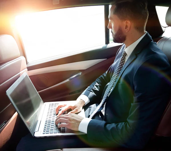 Uomo d'affari che lavora con il computer portatile seduto in auto — Foto Stock