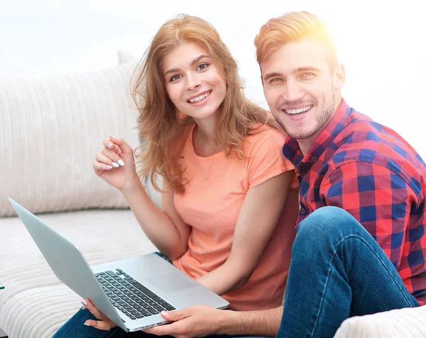 Pair students with a laptop sitting on sofa — Stock Photo, Image