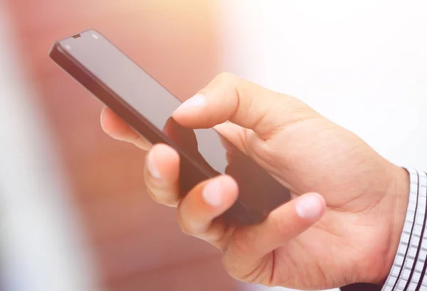 Primer plano. Un hombre sostiene un teléfono inteligente . — Foto de Stock