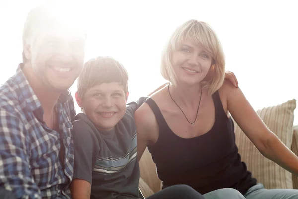 I genitori e il loro figlio si siedono rannicchiati nel soggiorno e sorridono — Foto Stock