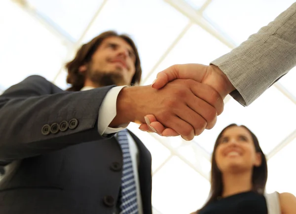 Empresarios estrechando la mano contra la habitación con grandes ventanales — Foto de Stock