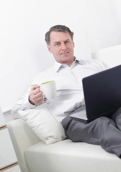 Geschäftsmann trinkt Tee und arbeitet im Hotelzimmer am Laptop — Stockfoto