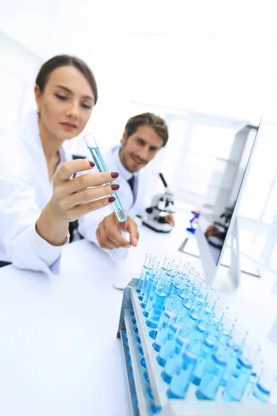 Donna che guarda le provette con liquidi colorati — Foto Stock