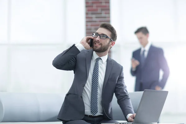 Confident young man talking on phone in office — Stock Photo, Image