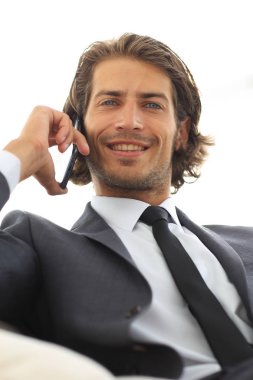 iş adamı rahat bir sandalyede otururken Smartphone'da konuşuyor.