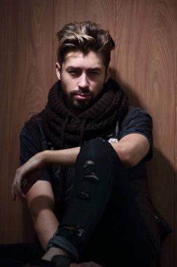 Sıradan giyinmiş sakallı bir adam oturur.