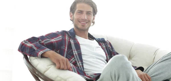 Primer plano de un chico sonriente acariciando a su perro mientras está sentado en un sillón grande . —  Fotos de Stock