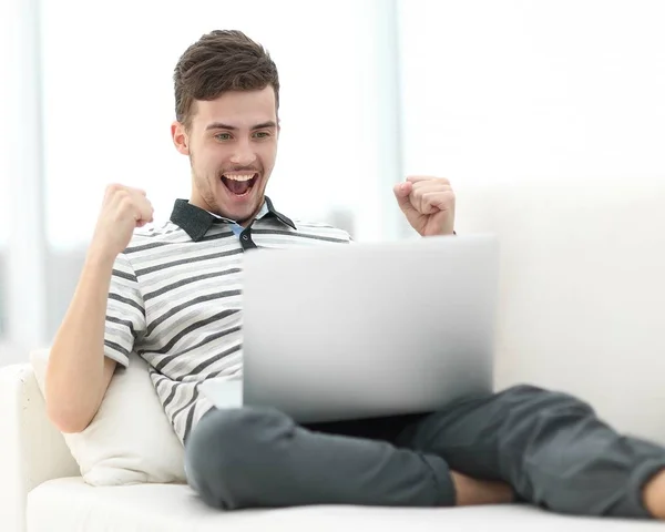 ソファに座ってノート パソコンを持つ幸せな男 — ストック写真