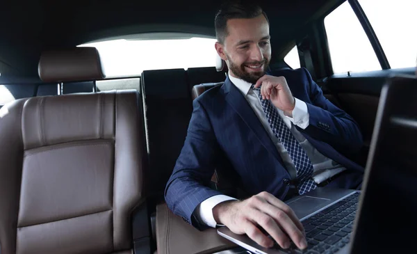 Hombre de negocios lee información sobre el ordenador portátil mientras está sentado en el coche — Foto de Stock